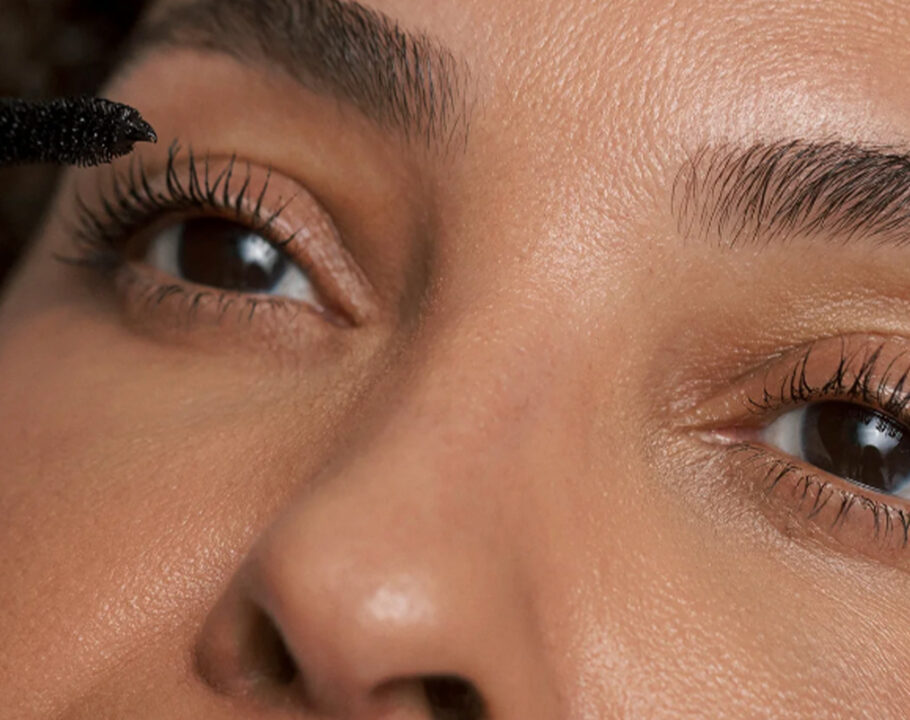 A close up of a woman's upper half of her face as she puts on mascara